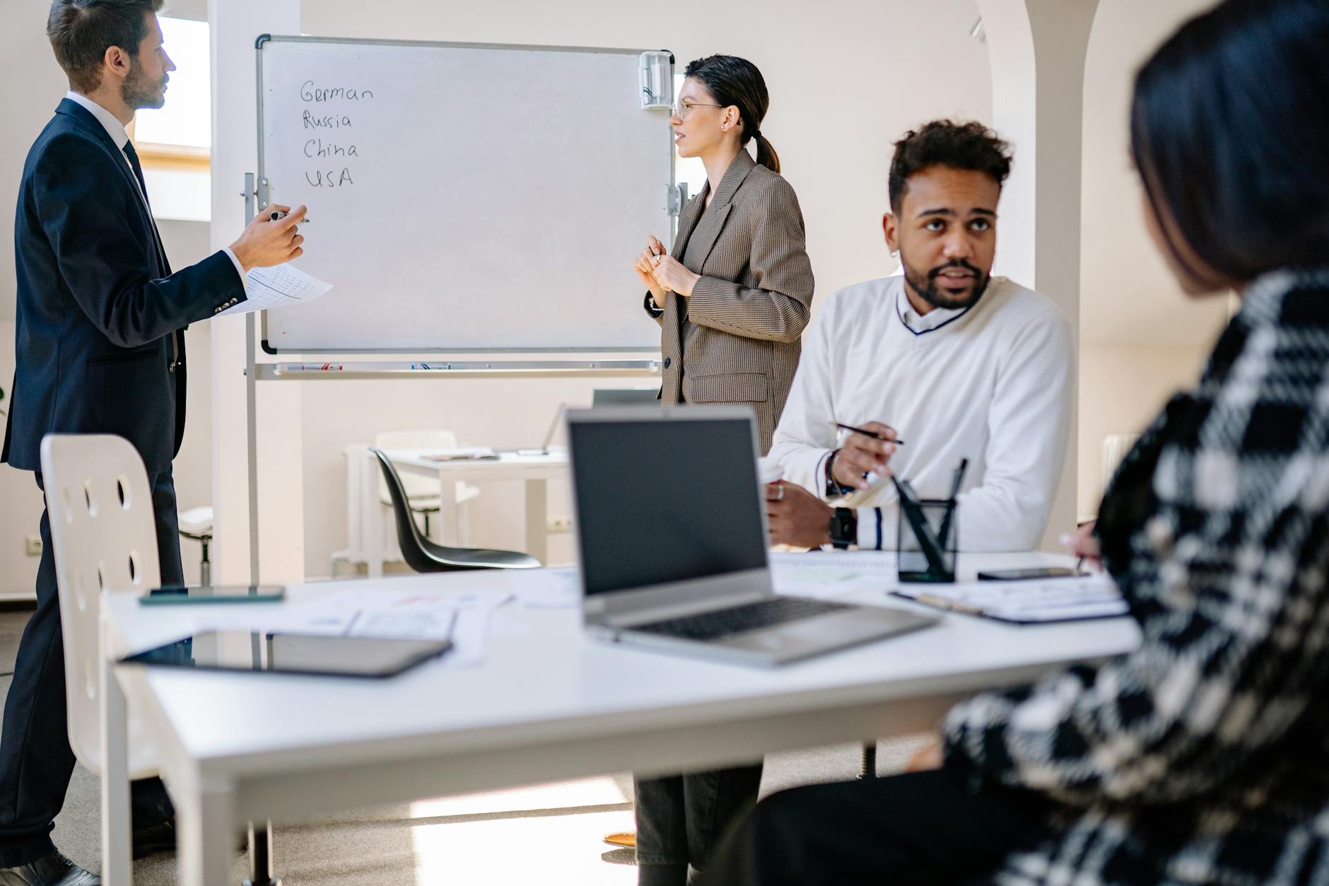 A diverse group of professionals collaborating around a table with a laptop and whiteboard